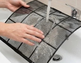Người dùng đang vệ sinh lưới lọc bụi để khắc phục điều hòa chảy nước